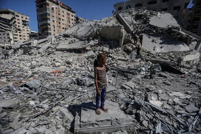 Palestinians walk through the rubble of the Tiba tower which crashed to the ground moments after Israeli strikes-stock-foto