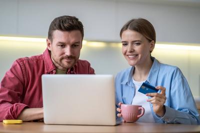 Happy couple sits with credit card at laptop, shopping online in kitchen, browsing marketplace deals Happy romantic coup-stock-foto