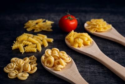 Augsburg, Bavaria, Germany - 19 October 2023: Three wooden spoons with raw noodles. Fusilli, farfalle and trulli pasta d-stock-foto