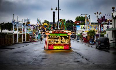 Eine Verk?uferin steht im Mandelstand und blickt auf ihr Handy am Morgen vor Er?ffnung des Oktoberfestes bei verregnetem-stock-foto