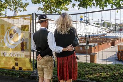 Oktoberfest wegen Bombendrohung geschlossen, ein Paar aus Passau, das eigentlich eine Reservierung im Festzelt hatte, schaut durch den Bauzaun auf das gesperrte Gel?nde, M?nchen, 1. Oktober 2025-stock-foto