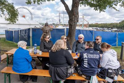 Oktoberfest wegen Bombendrohung geschlossen, auch alle Wiesn-Mitarbeiter mussten das Gel?nde verlassen, Mitarbeiter des Museumszelts versuchen das Beste aus ihrer misslichen Lage zu machen: Sie haben spontan zwei Bierb?nke und einen Tisch am S?deingang-stock-foto