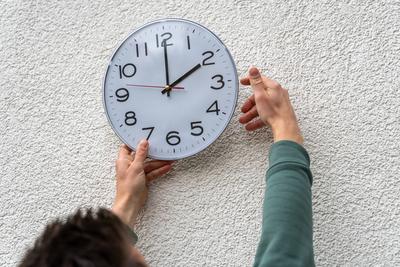 Augsburg, Bavaria, Germany - 17 October 2023: Man sets a clock hanging on the wall to winter time. Time change concept *-stock-foto
