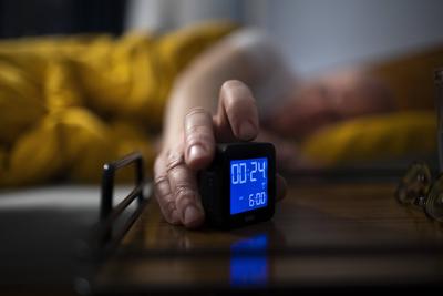 Thema: Schlaf. Mann liegt im Bett und schaltet seinen Wecker ein. Bonn Deutschland *** subject sleep man lies in bed and-stock-foto