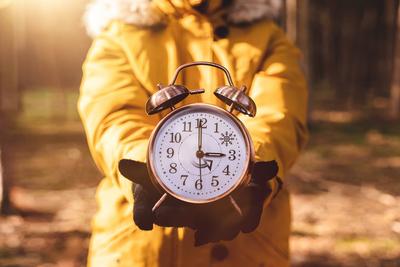 28 October 2022: Alarm clock in the hand of a woman, symbolic image time change from daylight saving time to winter tim-stock-foto