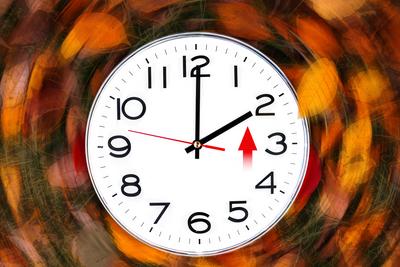 25 October 2024: Changeover of the clocks. Clock with autumn leaves in the background shows the time change from summer-stock-foto