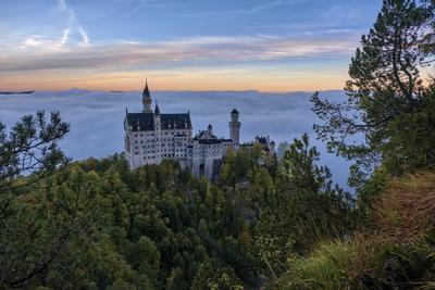 The castle Neuschwanstein, seen from the bridge Marienbr?cke at sunrise in autumn, rising out of the fog. Hohenschwangau-stock-foto