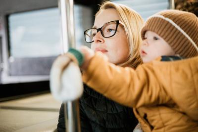 Mother carries her child while standing and holding on to the bus. Mom holding her infant baby boy in her arms while rid-stock-foto