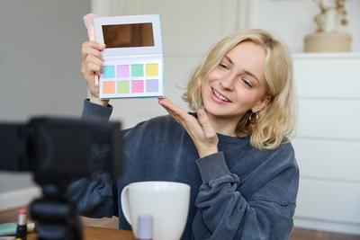 Portrait of beautiful lifestyle blogger, girl records a video on her camera for social media, shows palette of eyeshadow-stock-foto