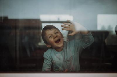Happy little boy waving through window to say goodbye when travelling in train. A happy little boy waving through window-stock-foto
