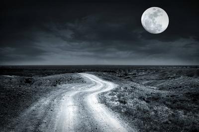 Empty rural road at full moon night Empty rural road going through prairie at full moon night with dramatic cloudy sky C-stock-foto