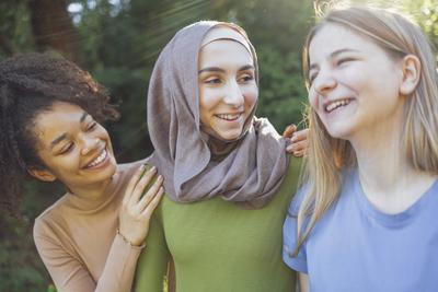 Multiracial young teen female friends walking in the park laughing Multiracial young teen female friends walking in the-stock-foto