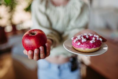 Diabetic woman is choosing between a fresh apple and a sweet doughnut. Diabetic woman is choosing between a fresh apple-stock-foto