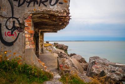 Abandoned remains of Northern forts of USSR View on ruined building on Liepaja beach against of endless waterscape, Latv-stock-foto