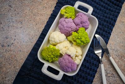 Wei?e und violette Blumenkohlr?schen und gr?ner, spiralf?rmiger Romanesco in einer Ofenform-stock-foto