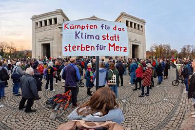 Internationaler Klimastreik von Fridays for Future, Demonstrantin mit Plakat K?mpfen f?r das Klima statt sterben f?r Merz, Kundgebung  auf dem K?nigsplatz, M?nchen, 14. November 2025-stock-foto