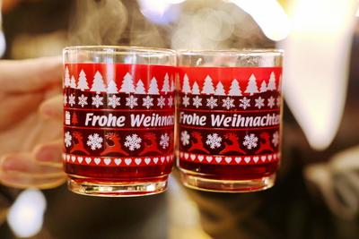 Feature Gl?hwein Hier: Zwei 2 Tassen Gl?hwein mit der Aufschrift Frohe Weihnachten werden hochgehalten auf dem Weihnacht-stock-foto