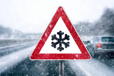 16 December: Sign warning of snow, cold and icy conditions in a snowstorm on the highway with moving vehicles PHOTOMONTA-stock-foto