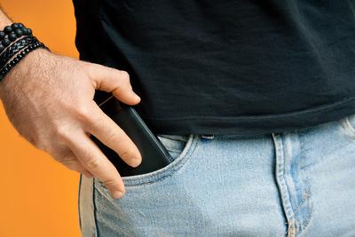 Closeup man take out mobile phone of his pocket Closeup man take out mobile phone of his pocket over yellow background ,-stock-foto