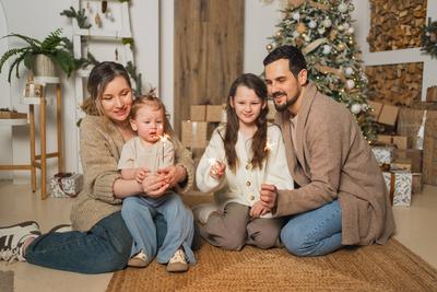 Frohe Weihnachten Gl?ckliche Familie Mutter Vater zwei Kinder mit glitzernden Wunderkerzen Kerze brennt in der N?he von Weihnachtsbaum. Eltern Kinder feiern Weihnachten genie?en die Winterferien zusammen. Familie Momente.-stock-foto