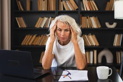 Kopfschmerzen. Frau mittleren Alters, die ihre Schl?fen ber?hrt und Stress empfindet. Reife alte Dame m?de von der Arbeit Gef?hl Kopfschmerzen krank Reiben Schl?fen Stirn. Lange Laptop-Nutzung Computer Vision B?ro-Syndrom.-stock-foto