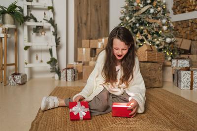 Frohe Weihnachten Xmas Urlaub. Teenager-M?dchen Auspacken ?ffnen Geschenk-Box in der N?he von Weihnachtsbaum. Teen kid Kind im Wohnzimmer mit Weihnachtsbaum ?ffnen Geschenk-Box mit ?berraschung Gesicht. Heiligabend zu Hause.-stock-foto