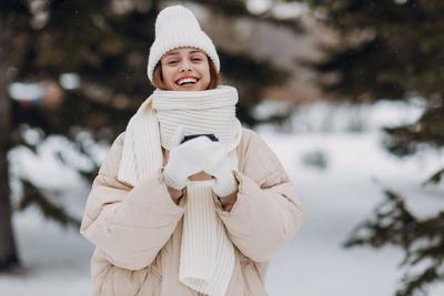 Happy smiling young woman portrait dressed coat scarf hat and mittens enjoys winter weather at snowy winter park. Happy-stock-foto