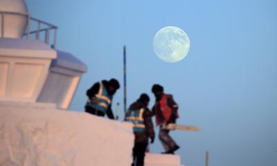 HARBIN, CHINA - DECEMBER 04: A full moon lights up the sky with workers brave cold to build snow sculpture at the constr-stock-foto