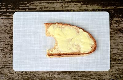 Ein Butterbrot Brot und Butter Butterbrot angebissen Fr?hst?cksbrettchen Resopal Brotscheibe Brotschnitte Fett Grundnah-stock-foto