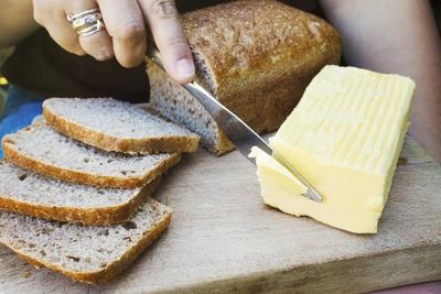 A person with a knife slicing through a block of butter for a sliced bread loaf. A person with a knife slicing through a-stock-foto