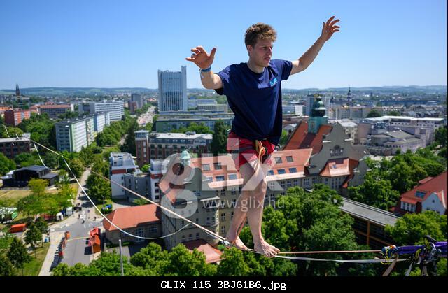 Chemnitz, Germany. 13th June, 2025. Slackliner Ruben Langer balances on a highline in front of the city center of Chemnitz. The Dresden native is an experienced highliner and has already set two world records. As part of the 'Kosmos Festival' (13.-15.06.2025), he and 17 other athletes from five clubs will be competing on three lines in the city area. The athletes will move up to 45 meters above the ground. Credit: Hendrik Schmidt/dpa/Alamy Live News