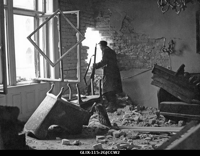 BUDAPEST 1956 Egy magyar felkelő őrködik egy lerombolt lakásban Budapest belvárosában, a Magyar Népköztársaság és a szovjetek által kényszerített p...