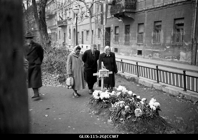 BUDAPEST 1956 Emberek gyászolnak egy rögtönzött sírnál egy budapesti központi utcán a Magyar Népköztársaság és a szovjetek által kényszerített poli...