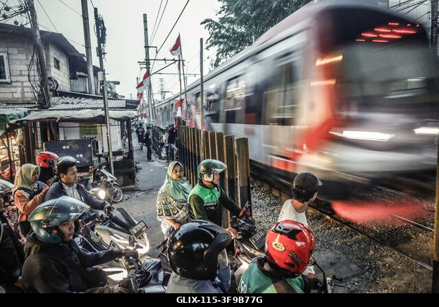 JAKARTA, INDONÉZIA, 2026. AUGUSZTUS 14.: Egy motoros vonatra vár egy vasúti átjárónál Gambir Roxy negyedében, Jakartában. A PT Kereta Api Indonesia...
