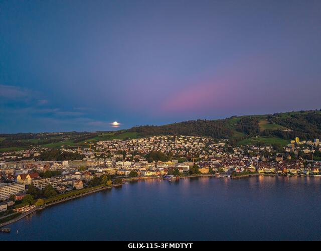 Drónfelvétel a svájci Zug városára a Zugersee tópartján, holdkeltével a kék óra idején.